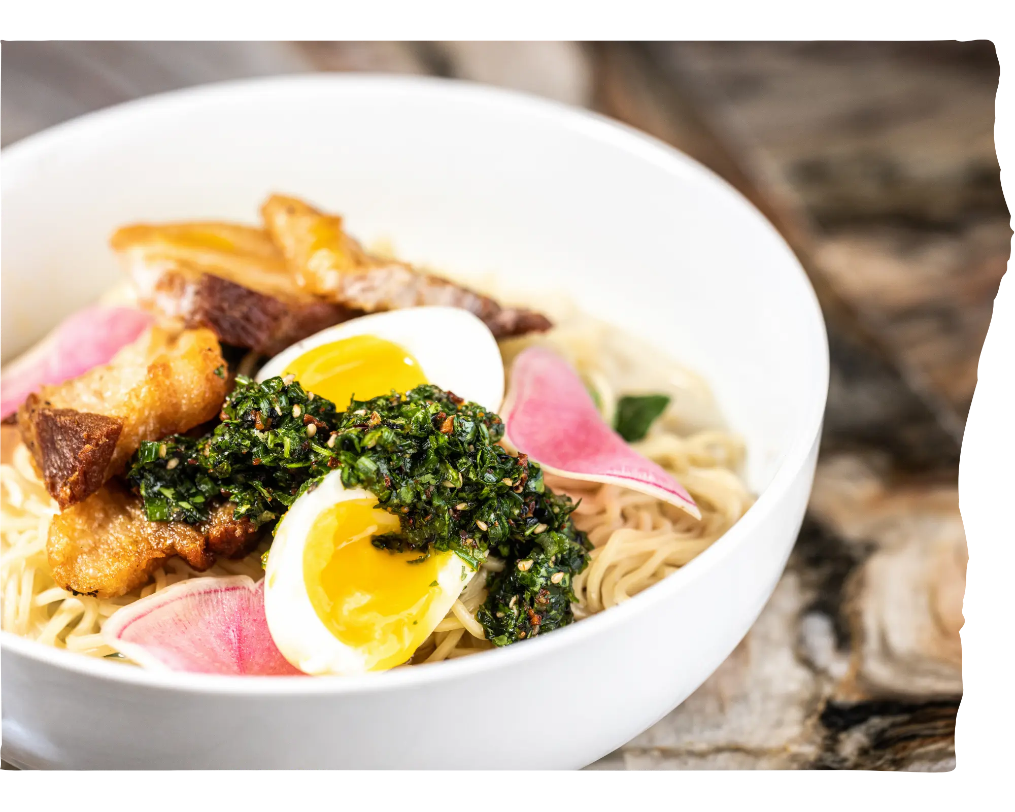 A bowl of ramen with eggs and pork belly.